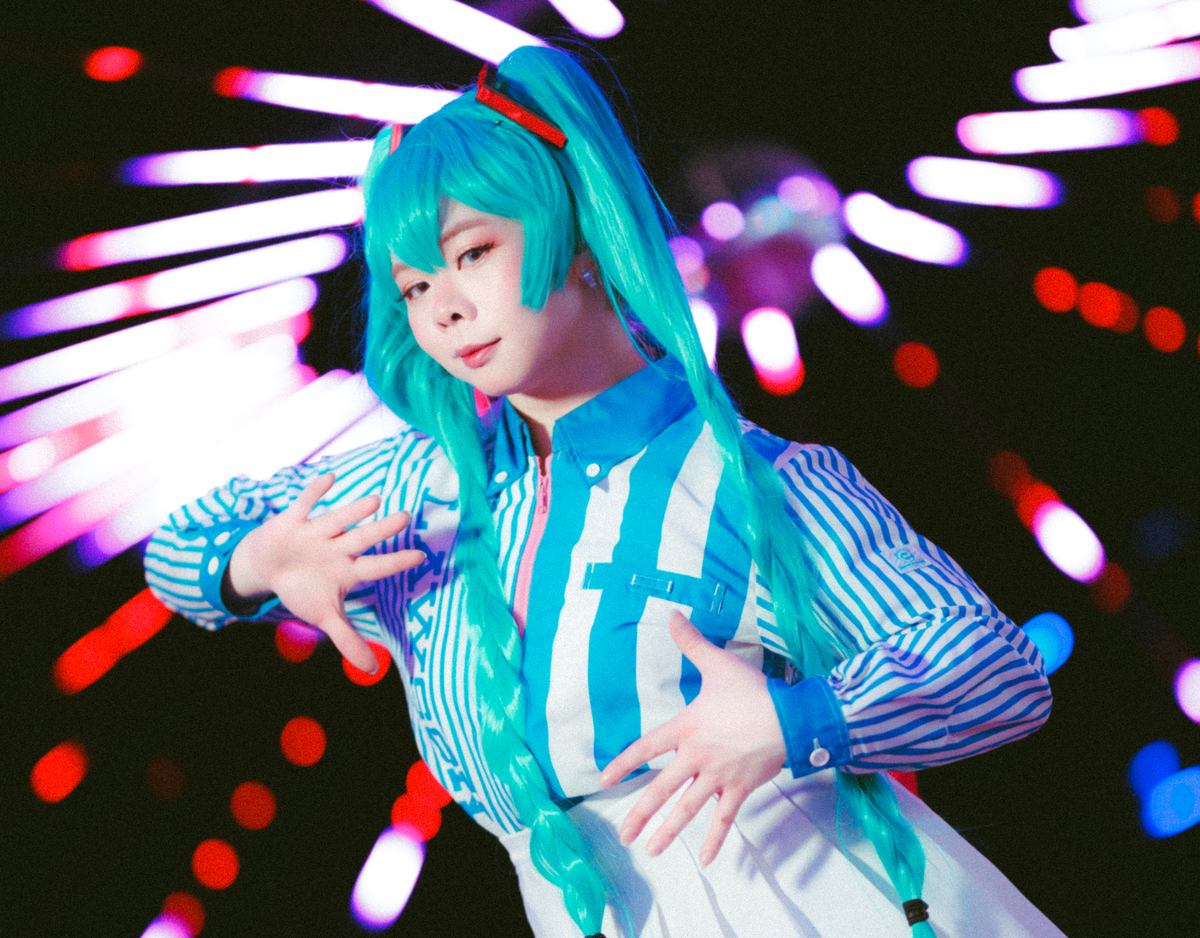 Meet Kuro the latest Idol to hit the scene. Image of Kuro in a Hatsune Miku cosplay on set for their debut single video at a roller skating rink.